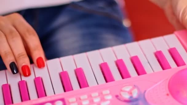 Vrouw op toetsenbord knoppen van speelgoed piano spelen — Stockvideo
