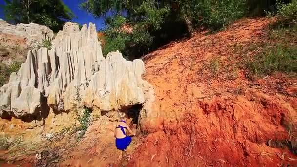 Chica sube y juega en la orilla rocosa — Vídeo de stock