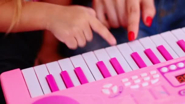 Meisje en vrouw speelt op speelgoed piano klavier — Stockvideo