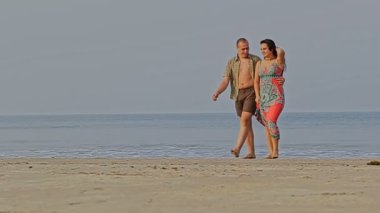 Tropik sahilde yürüyen bir çift.