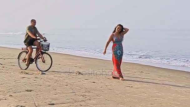 Man on bicycle catches girl on beach — Stock Video