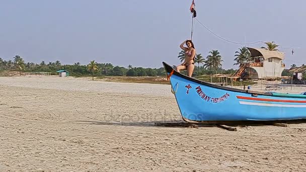 Senhora senta-se no barco contra a praia do oceano — Vídeo de Stock