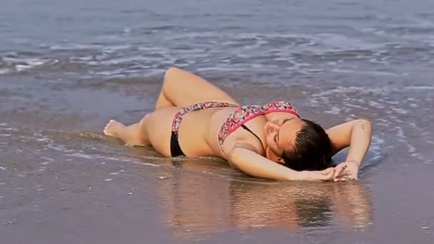 Девушка в купальнике лежит на тропическом пляже — стоковое видео