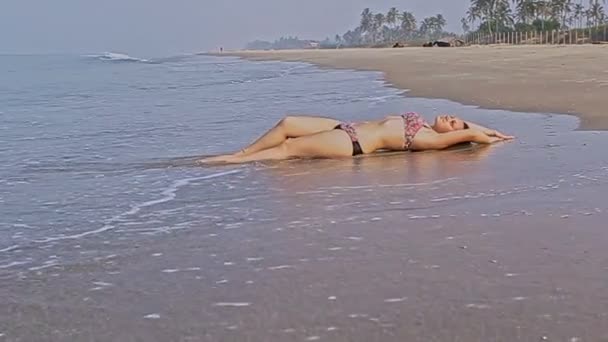 Дівчина в купальнику лежить на тропічному пляжі — стокове відео