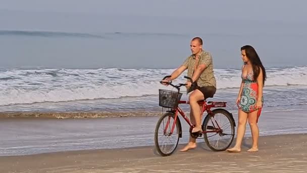 Man on bicycle catches girl on beach — Stock Video