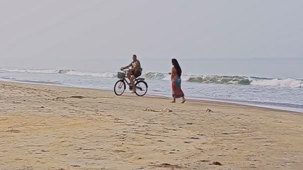 Чоловік на велосипеді ловить дівчину на пляжі — стокове відео