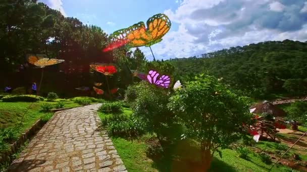 Walkway among tropical plants and artificial butterflies — Stock Video