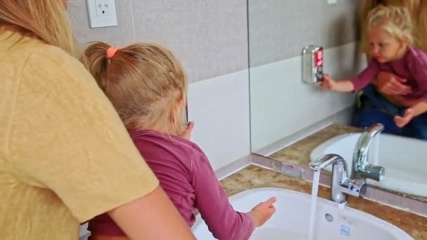 Mother and daughter washes hands in public toilet — Stock Video