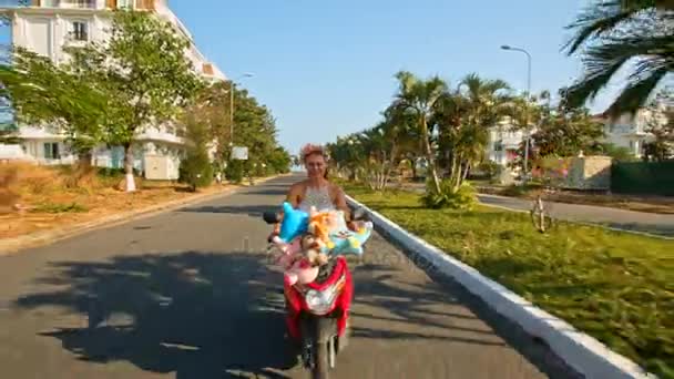 dívka rychlostí na mopedu s hračkami se podél silnice 