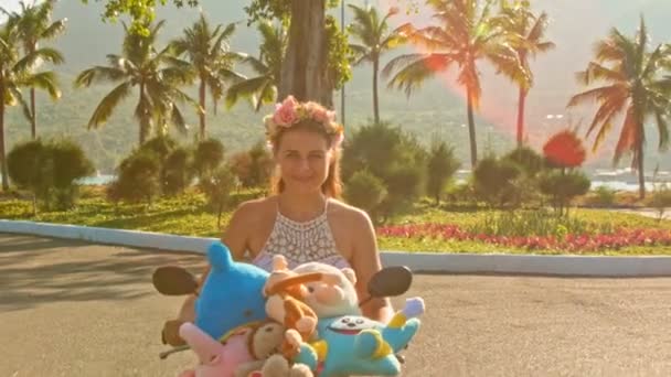Girl speeds on moped with toys with along road — Stock Video
