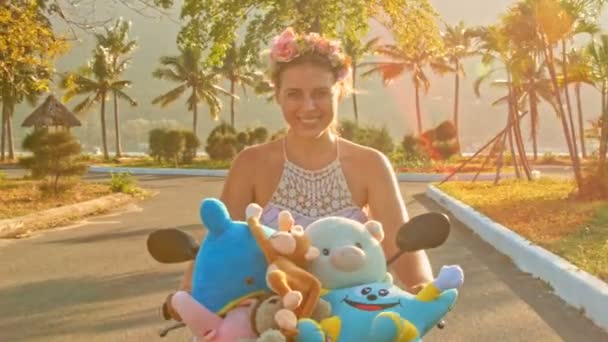 Dívka rychlostí na mopedu s hračkami se podél silnice — Stock video