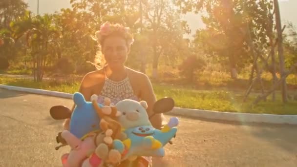 Girl speeds on moped with toys with along road — Stock Video