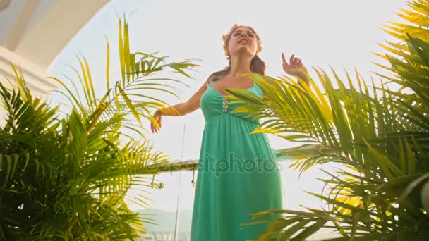 Ragazza balla e canta tra le palme sul balcone — Video Stock