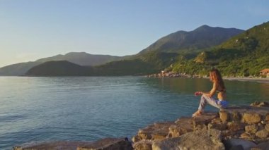 Kız kumsalda oturur ve deniz manzarası sever