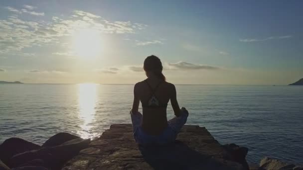 Flicka gör yoga på klippstrand — Stockvideo