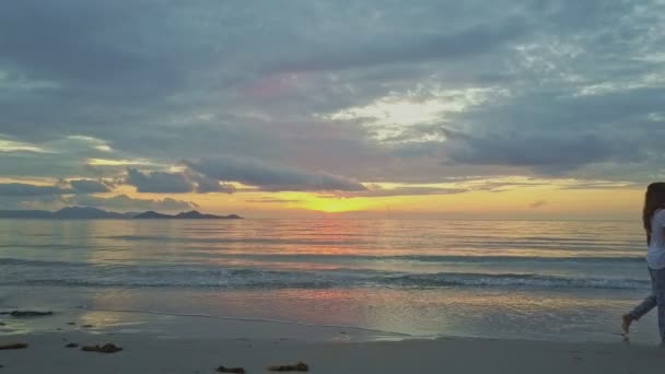 Mädchen spaziert bei Sonnenaufgang am Sandstrand — Stockvideo