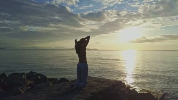Chica hace yoga en la playa rocosa — Vídeo de stock