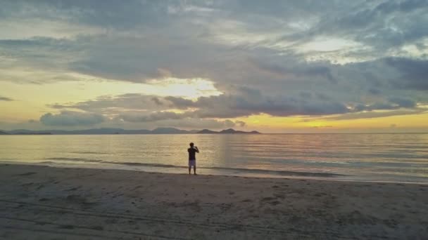 Hombre tomando fotos de paisajes marinos al amanecer — Vídeos de Stock