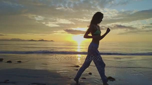 Chica corre a lo largo de la playa de arena al amanecer — Vídeos de Stock
