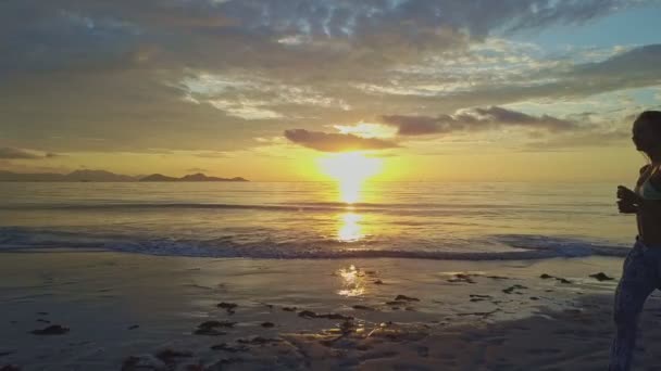 Menina corre ao longo praia de areia ao nascer do sol — Vídeo de Stock