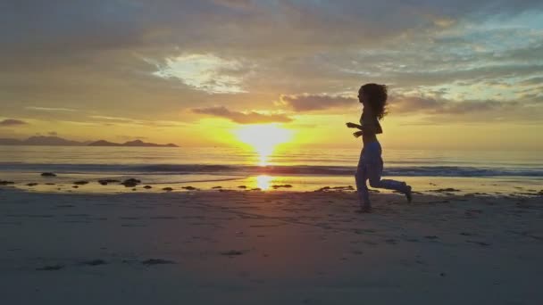 Chica corre a lo largo de la playa de arena al amanecer — Vídeos de Stock