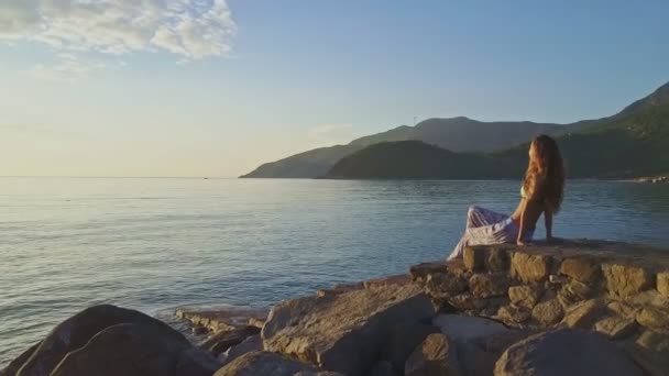 Menina senta-se na praia e gosta de paisagem marinha — Vídeo de Stock