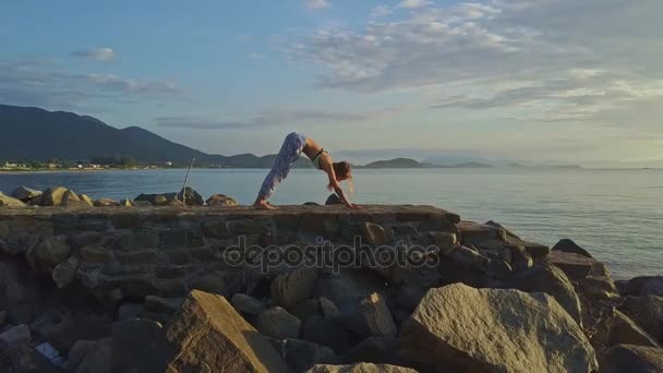 Girl does yoga on rocky beach — Stock Video