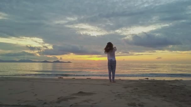 Chica haciendo selfie en la orilla del mar contra la salida del sol — Vídeos de Stock