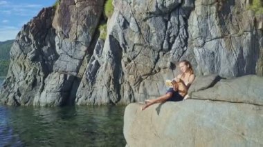 Kız rock kıyısında kitap okuma
