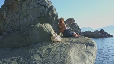 Kız rock kıyısında kitap okuma