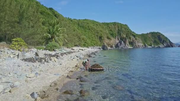 Mann zieht Boot mit Algen an Strand — Stockvideo