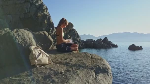 Niña leyendo libro en la costa de roca — Vídeo de stock