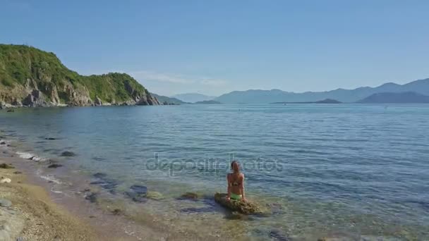 Дівчина сидить на скелі в морі — стокове відео