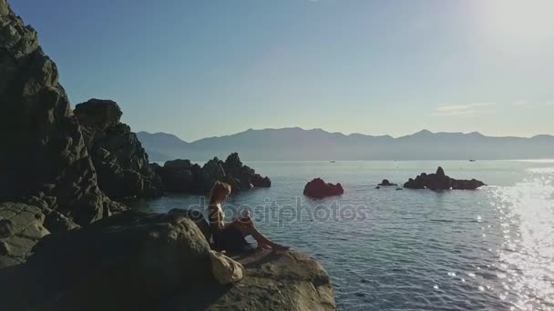 Niña leyendo libro en la costa de roca — Vídeos de Stock