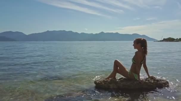Chica sentada en la roca en el mar — Vídeos de Stock