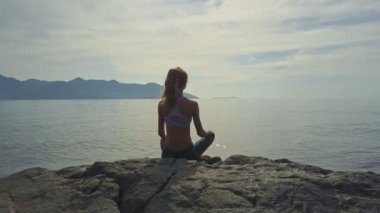 kayalık okyanus kıyısında yoga yaparken kız