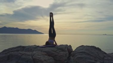 kayalık okyanus kıyısında yoga yaparken kız