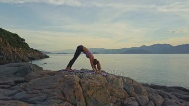 kayalık okyanus kıyısında yoga yaparken kız