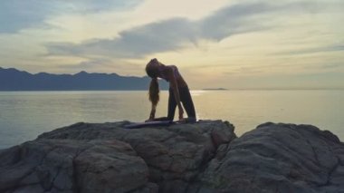 kayalık okyanus kıyısında yoga yaparken kız