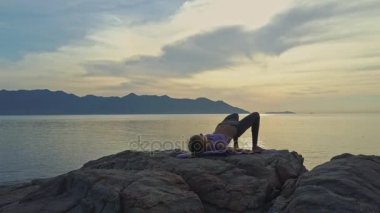 kayalık okyanus kıyısında yoga yaparken kız