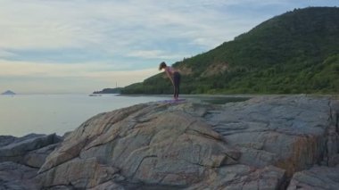 kayalık okyanus kıyısında yoga yaparken kız