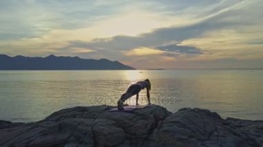 kayalık okyanus kıyısında yoga yaparken kız