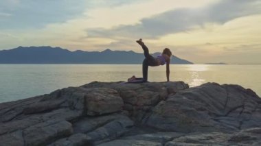 kayalık okyanus kıyısında yoga yaparken kız