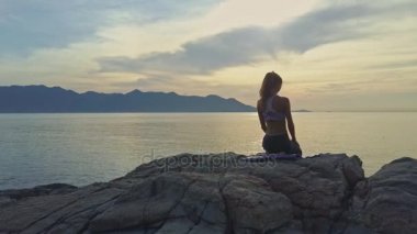 kayalık okyanus kıyısında yoga yaparken kız