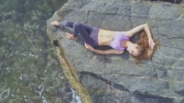 Güneş ışınları altında kayalık plajda kız yatıyor 