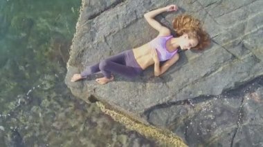 Güneş ışınları altında kayalık plajda kız yatıyor   