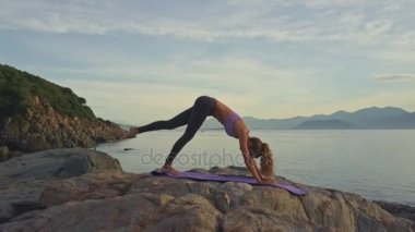 kayalık okyanus kıyısında yoga yaparken kız