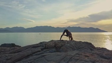 kayalık okyanus kıyısında yoga yaparken kız