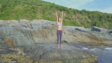 kayalık okyanus kıyısında yoga yaparken kız