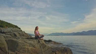 kayalık okyanus kıyısında yoga yaparken kız